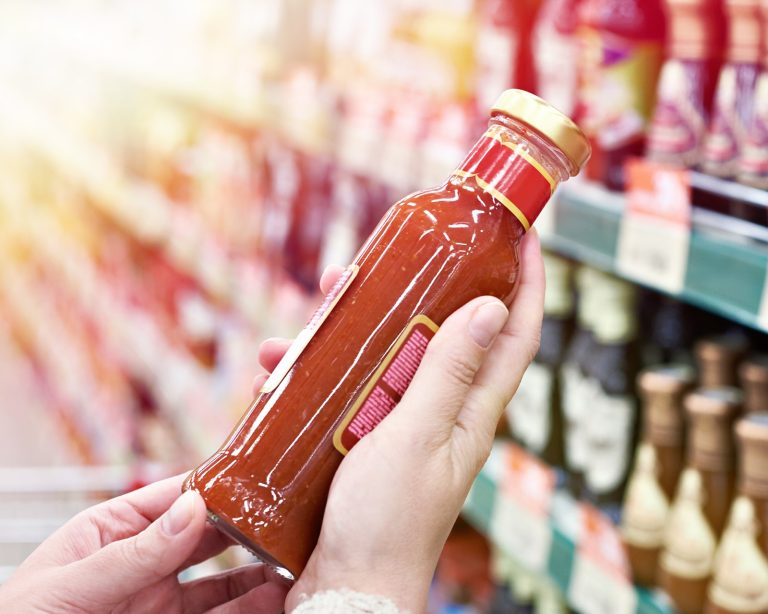 shopper holds glass bottle of hot sauce