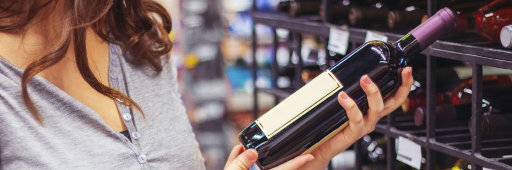 woman holds wine bottle in store aisle