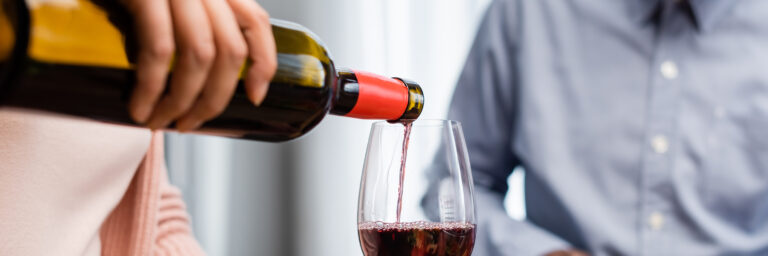 Wine being poured from a glass bottle into a glass.